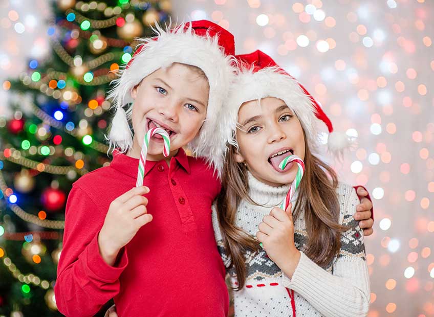 Happy children in christmas caps eating candy canes